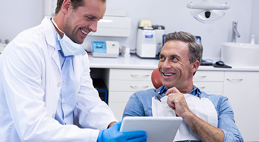 Smiling patient in dental chair talking to his dentist