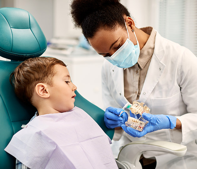 Dental hygienist explaining to child how to brush effectively