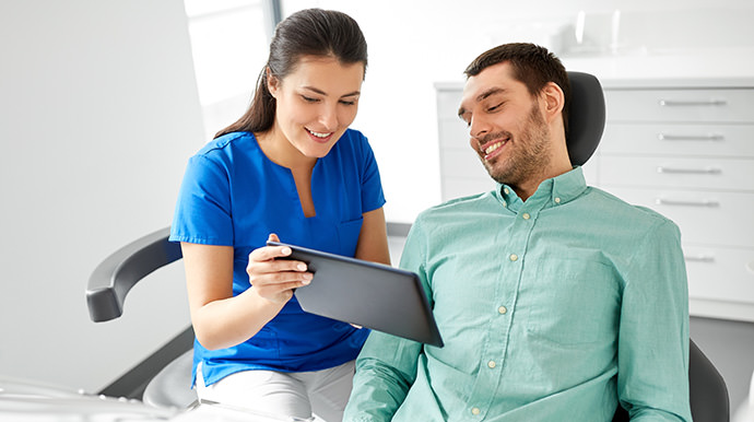 Dentist showing patient a computer tablet.