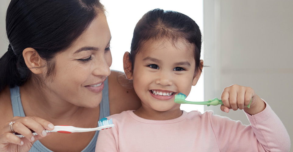 Mother brushing teeth with daughter