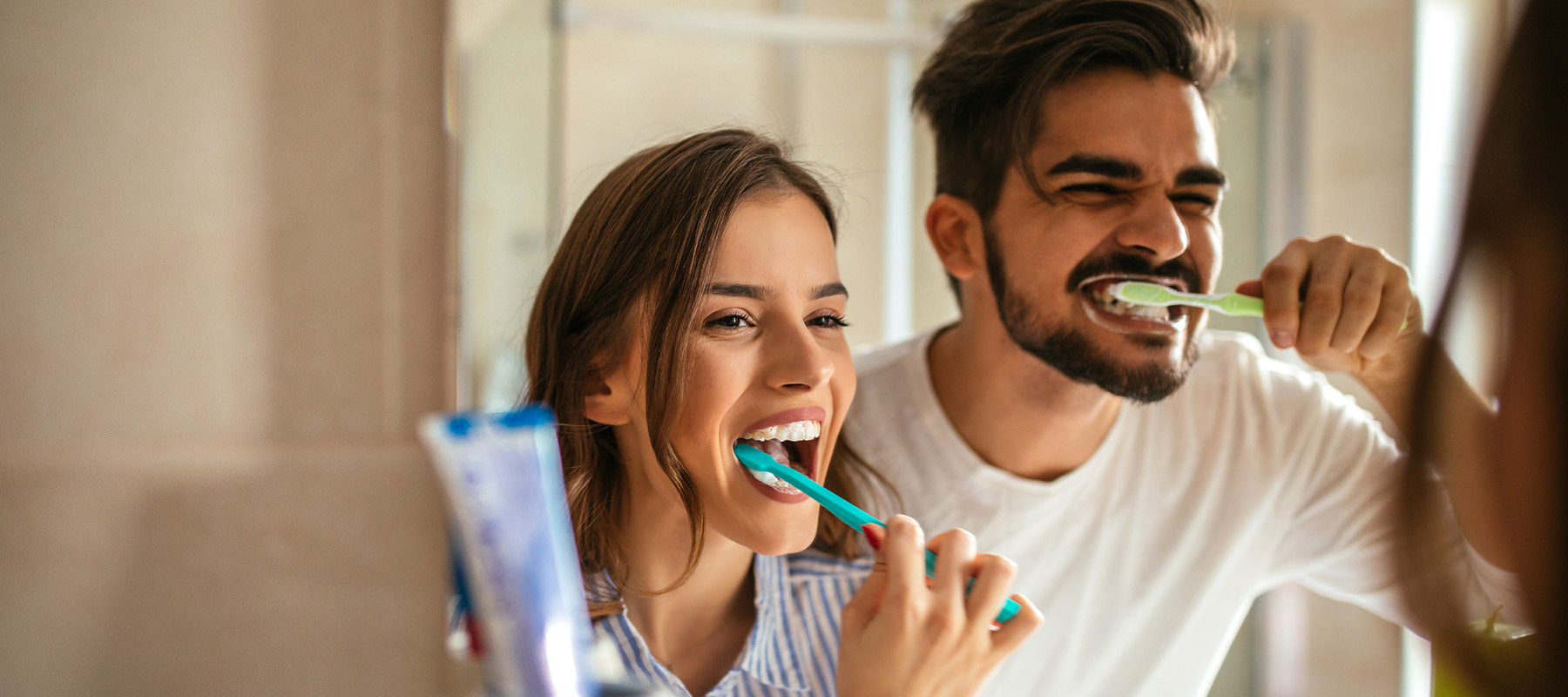 Smiling couple brushing their teeth