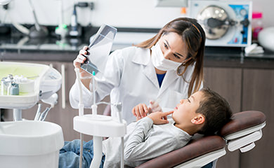 Dentista con niño paciente en sillón dental