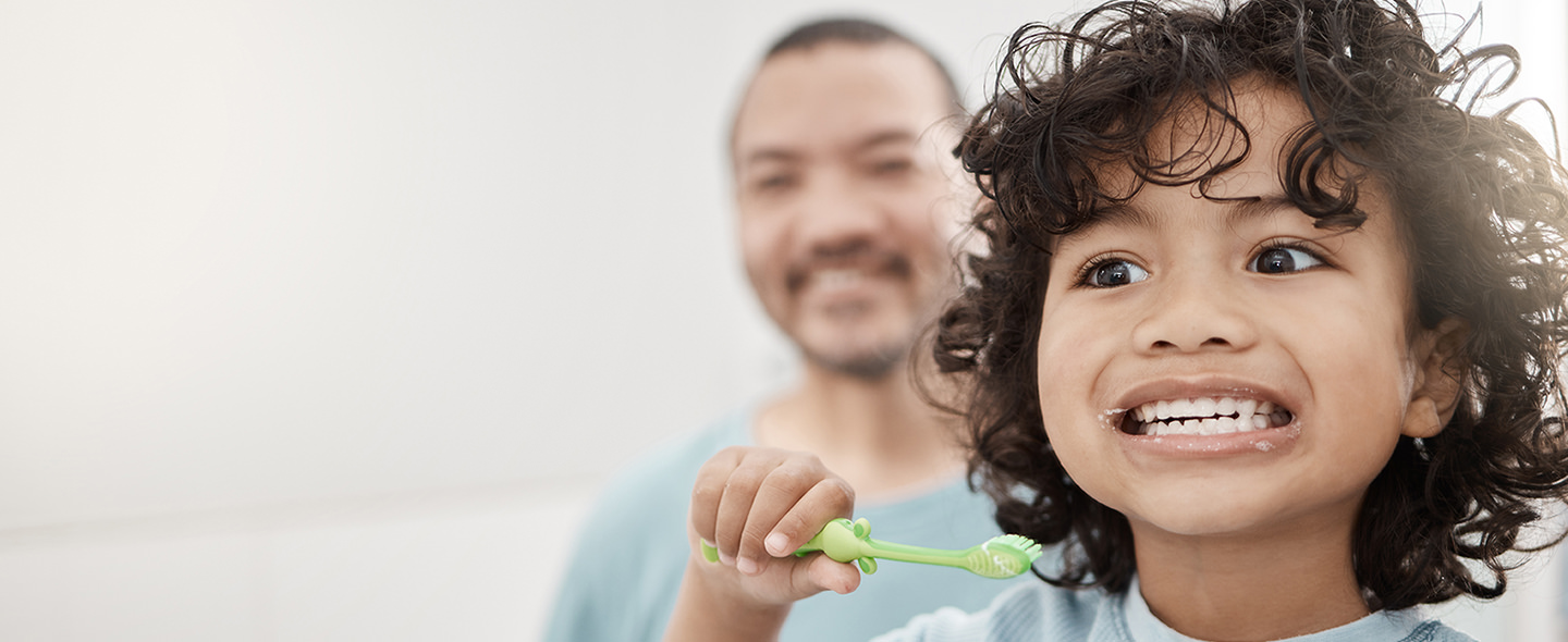 Kid brushing teeth with dad watching