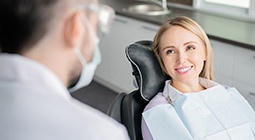 Smiling patient in dental chair talking to her dentist