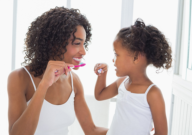 Mother and daughter brushing teeth
