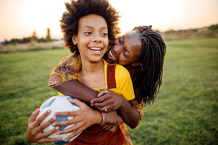 Woman hugging kid with soccer ball