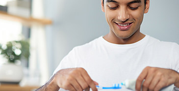 Man putting toothpaste on a toothbrush