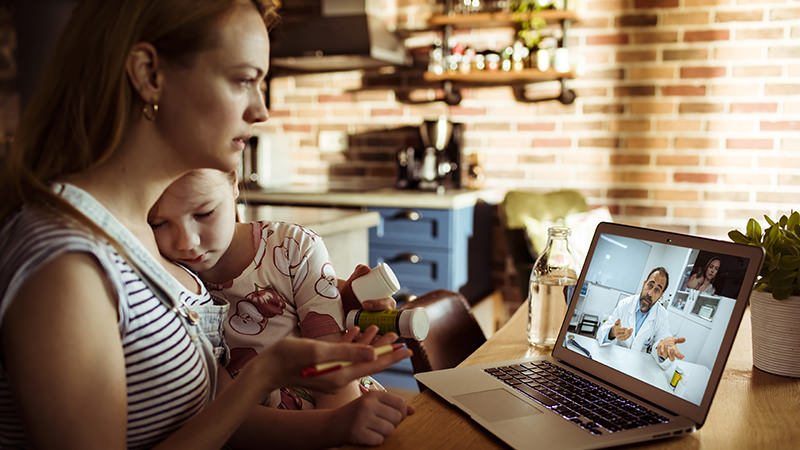 Woman looking at laptop screen with child next to her